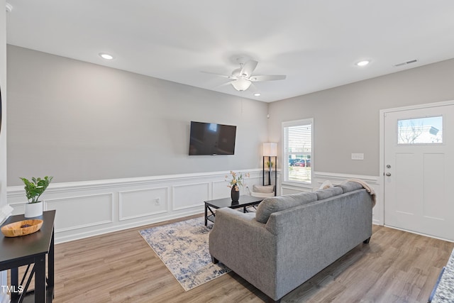 living room featuring a wainscoted wall, light wood finished floors, a ceiling fan, and recessed lighting