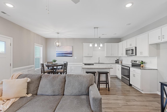 kitchen with open floor plan, appliances with stainless steel finishes, a sink, and visible vents