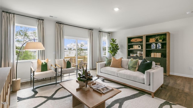 living room featuring plenty of natural light, wood finished floors, visible vents, and baseboards