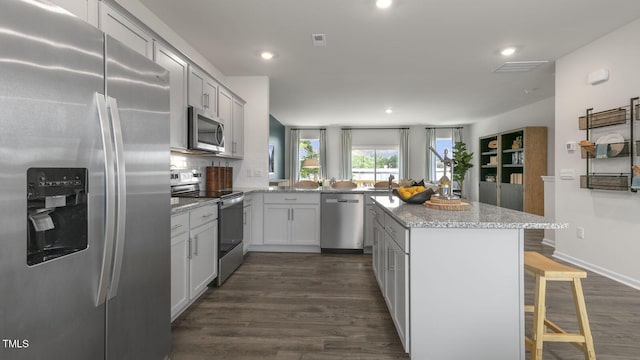 kitchen featuring stainless steel appliances, dark wood-style flooring, backsplash, and a kitchen breakfast bar