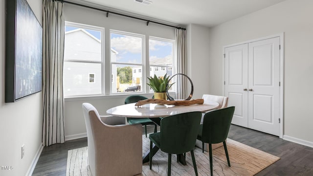 dining space with dark wood-style flooring, visible vents, and baseboards