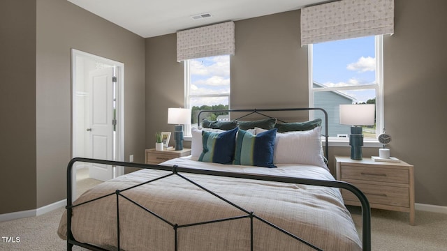 bedroom with light carpet, multiple windows, visible vents, and baseboards