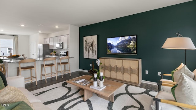 living room featuring dark wood-style floors, an accent wall, baseboards, and recessed lighting