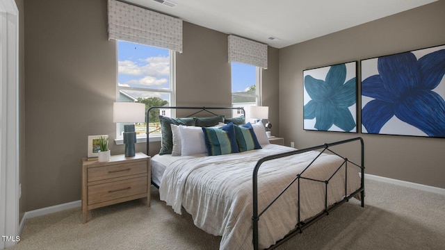 bedroom with multiple windows, light carpet, and baseboards