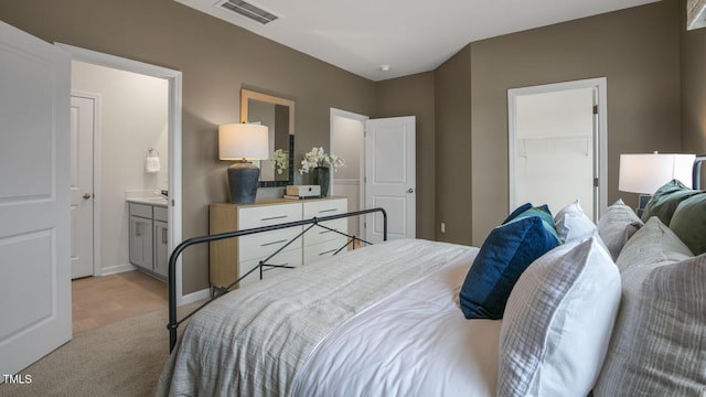 bedroom featuring a walk in closet, a closet, visible vents, ensuite bath, and baseboards