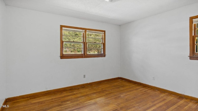 unfurnished room featuring wood-type flooring, baseboards, and a textured ceiling