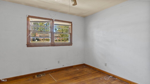 empty room with baseboards, visible vents, and hardwood / wood-style floors