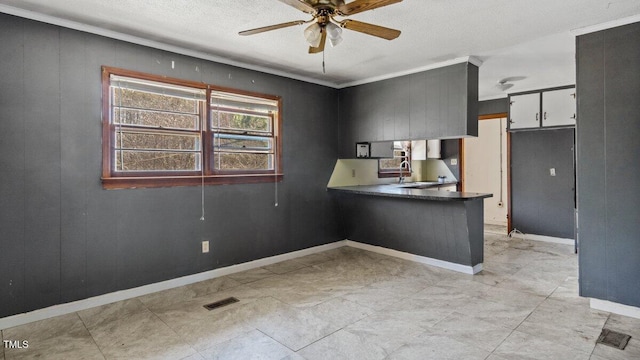 kitchen featuring a peninsula, a sink, visible vents, a ceiling fan, and dark countertops