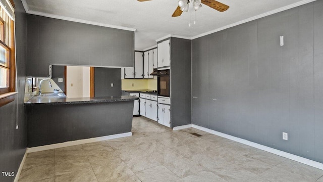 kitchen featuring dark countertops, black oven, crown molding, and a sink