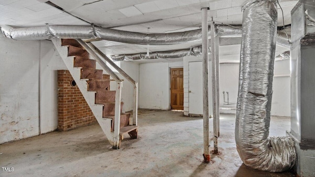 unfinished basement featuring stairway and concrete block wall