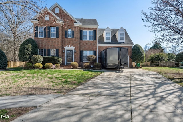 view of front of home featuring driveway, brick siding, a front lawn, and fence