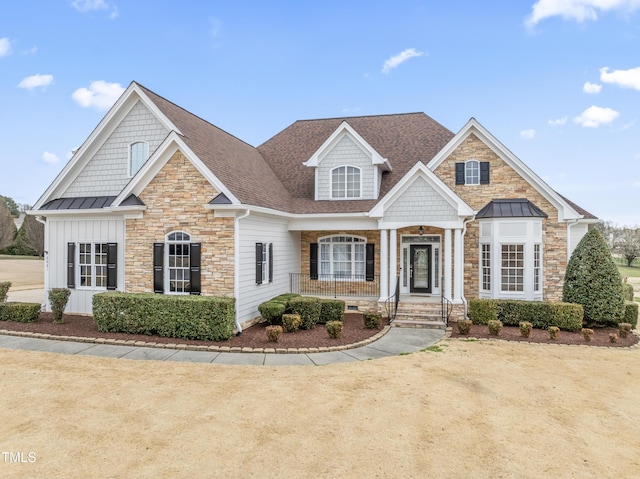 view of front of house featuring board and batten siding, stone siding, roof with shingles, and a standing seam roof