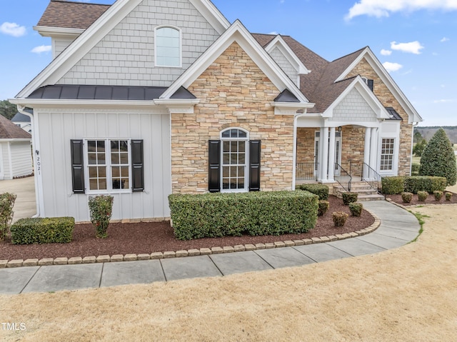 view of front of house featuring a standing seam roof, stone siding, a shingled roof, and board and batten siding