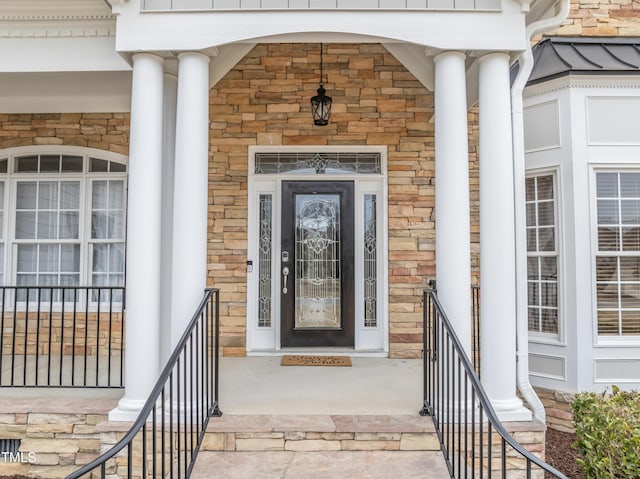 view of exterior entry with stone siding and covered porch