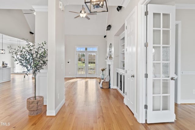 interior space with ornamental molding, a high ceiling, a fireplace, and light wood-style flooring