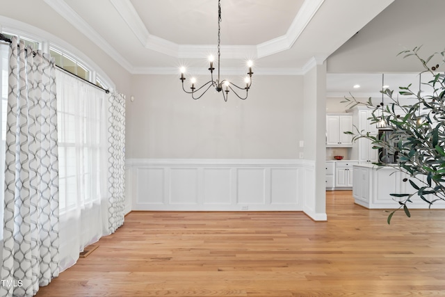 dining space featuring light wood finished floors, wainscoting, a tray ceiling, and plenty of natural light