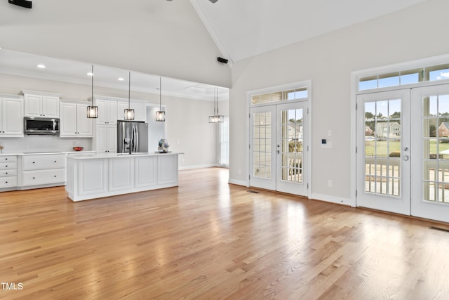 unfurnished living room featuring baseboards, french doors, light wood-style floors, high vaulted ceiling, and recessed lighting