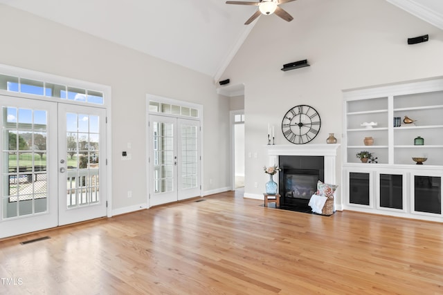 unfurnished living room with french doors, visible vents, light wood-style flooring, high vaulted ceiling, and a tile fireplace