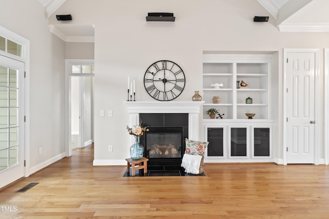 living area featuring ornamental molding, a tile fireplace, visible vents, and wood finished floors