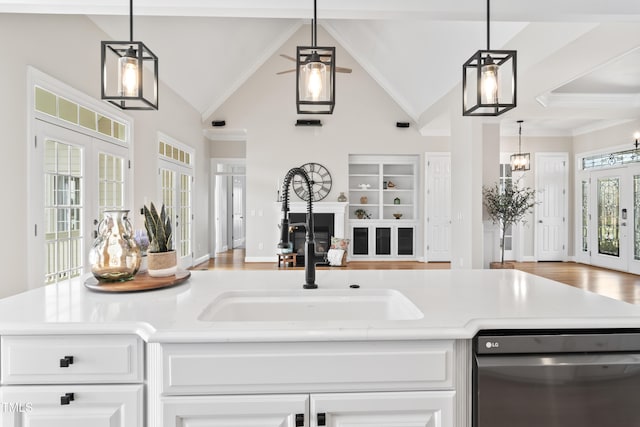 kitchen featuring french doors, light countertops, stainless steel dishwasher, open floor plan, and a sink