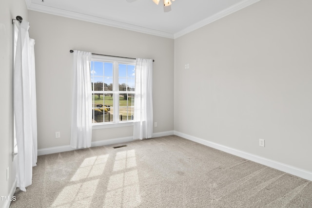 carpeted spare room featuring baseboards, visible vents, a ceiling fan, and ornamental molding