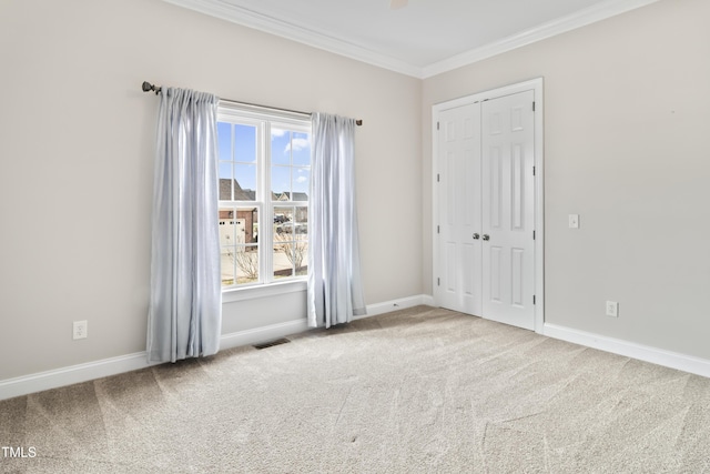 empty room with carpet floors, ornamental molding, visible vents, and baseboards