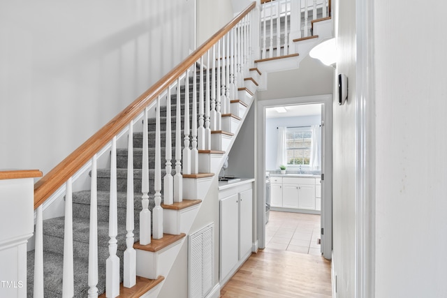 stairs featuring visible vents, wood finished floors, and a towering ceiling