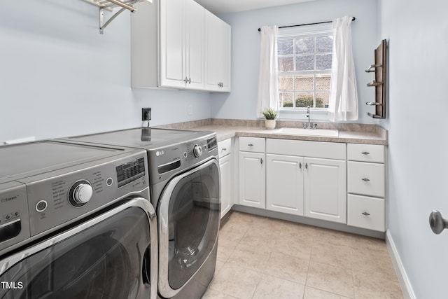 laundry area featuring light tile patterned flooring, a sink, baseboards, independent washer and dryer, and cabinet space