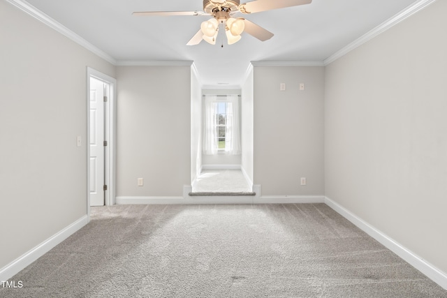 carpeted empty room featuring a ceiling fan, crown molding, and baseboards