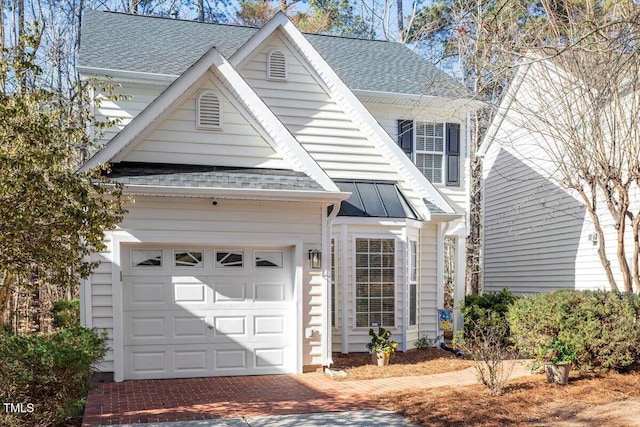 view of front of property with metal roof, an attached garage, decorative driveway, roof with shingles, and a standing seam roof