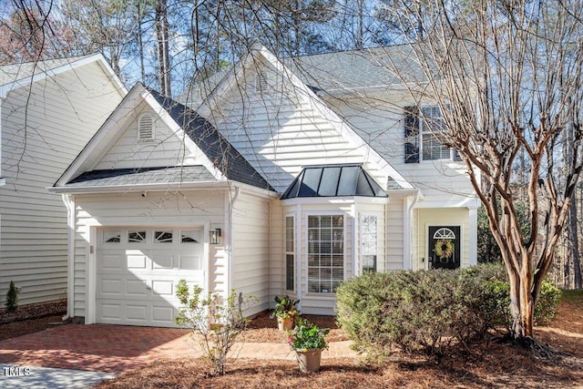 view of front of property with metal roof, an attached garage, a shingled roof, decorative driveway, and a standing seam roof