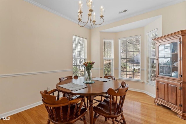 dining room featuring crown molding, light wood-style flooring, visible vents, and a healthy amount of sunlight