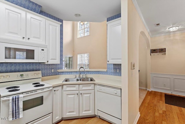 kitchen with crown molding, white appliances, light countertops, and a sink