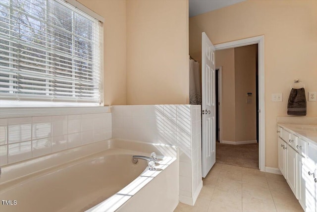 full bathroom with a garden tub, vanity, baseboards, and tile patterned floors