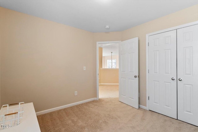 unfurnished bedroom featuring a closet, light colored carpet, and baseboards