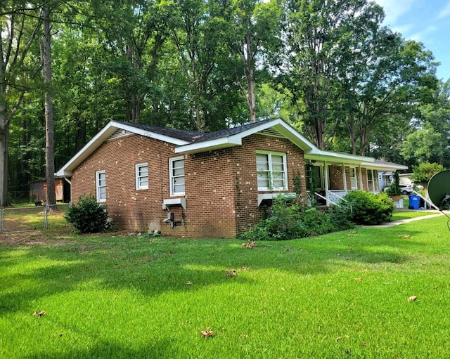 view of side of property with crawl space, brick siding, a lawn, and fence