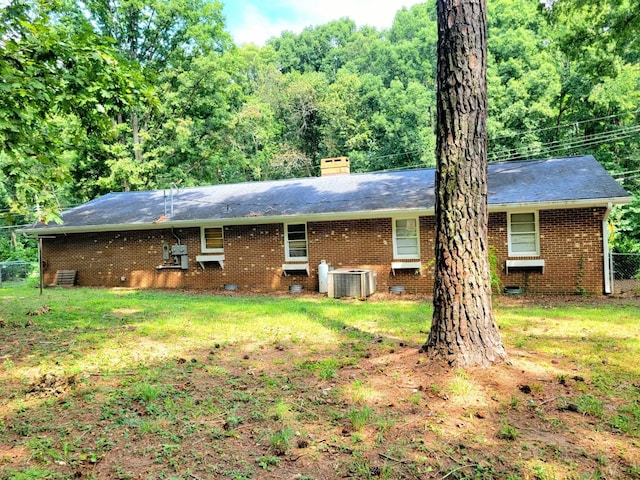 back of house featuring a chimney, crawl space, cooling unit, a yard, and brick siding