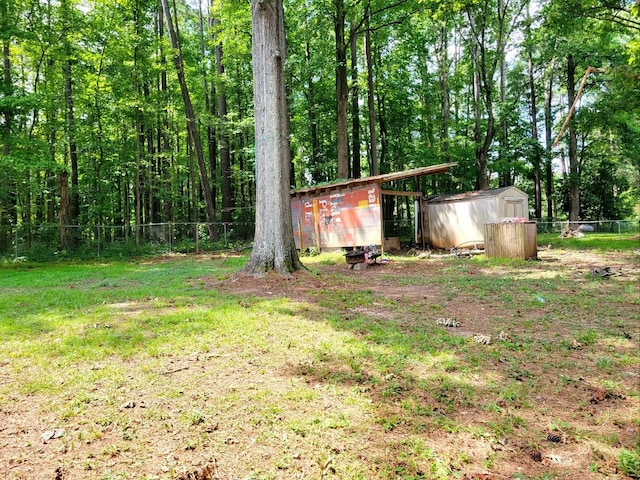 view of yard featuring a shed, fence, and an outbuilding