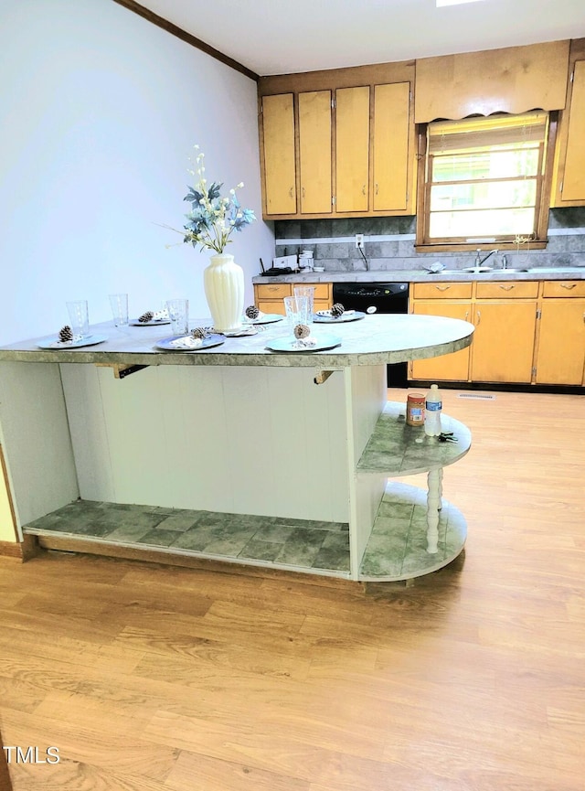 kitchen with ornamental molding, light wood-type flooring, a sink, and backsplash