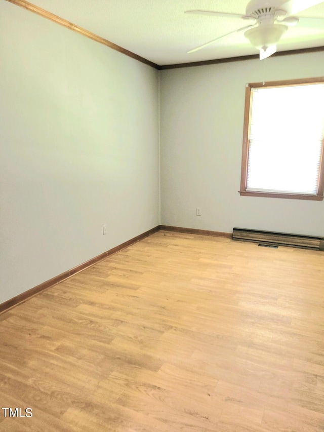 spare room with ornamental molding, baseboards, light wood-style flooring, and baseboard heating