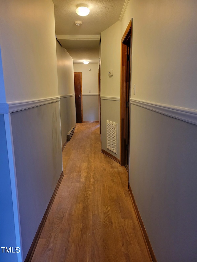 corridor featuring visible vents, a textured ceiling, and wood finished floors