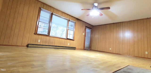 unfurnished room with a baseboard radiator, wooden walls, wood finished floors, a ceiling fan, and baseboards