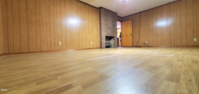 unfurnished living room with wood walls, a brick fireplace, and wood finished floors