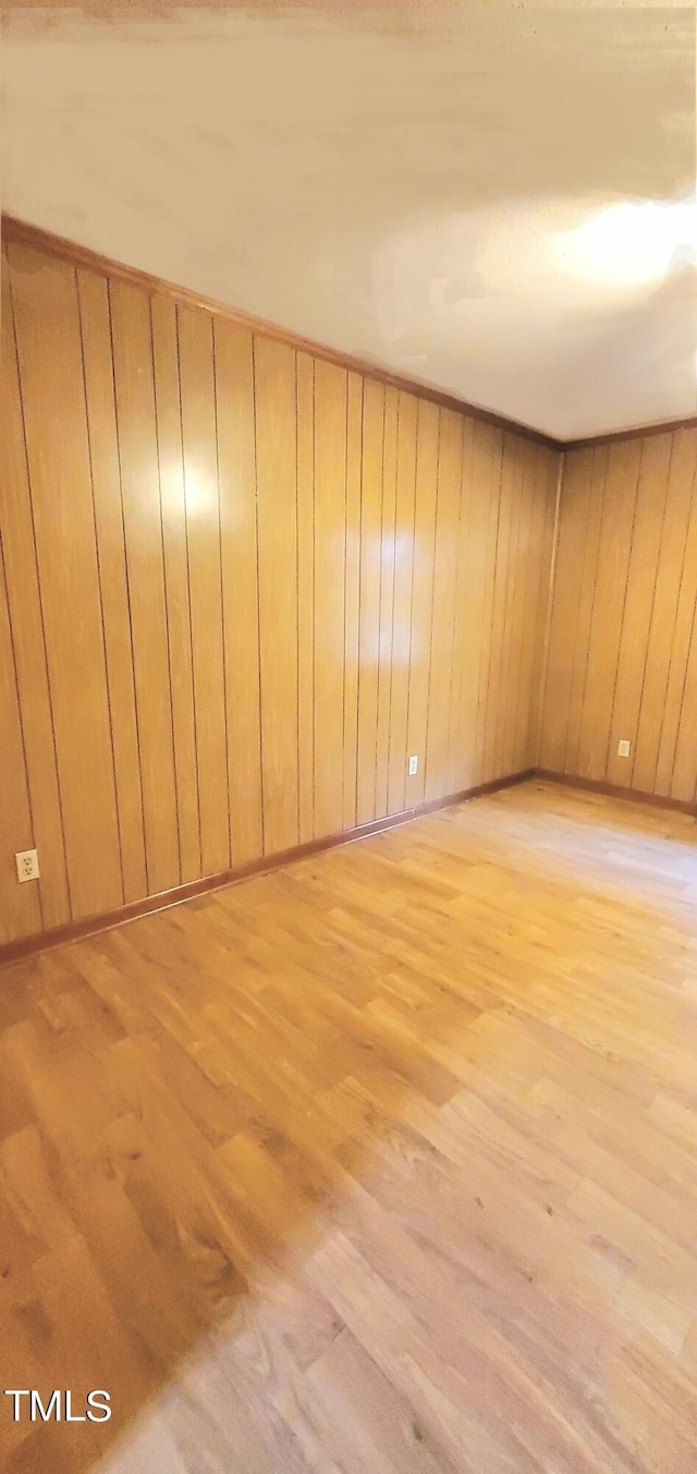 spare room with wood walls and light wood-type flooring