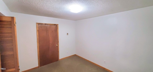 carpeted spare room featuring a textured ceiling and baseboards