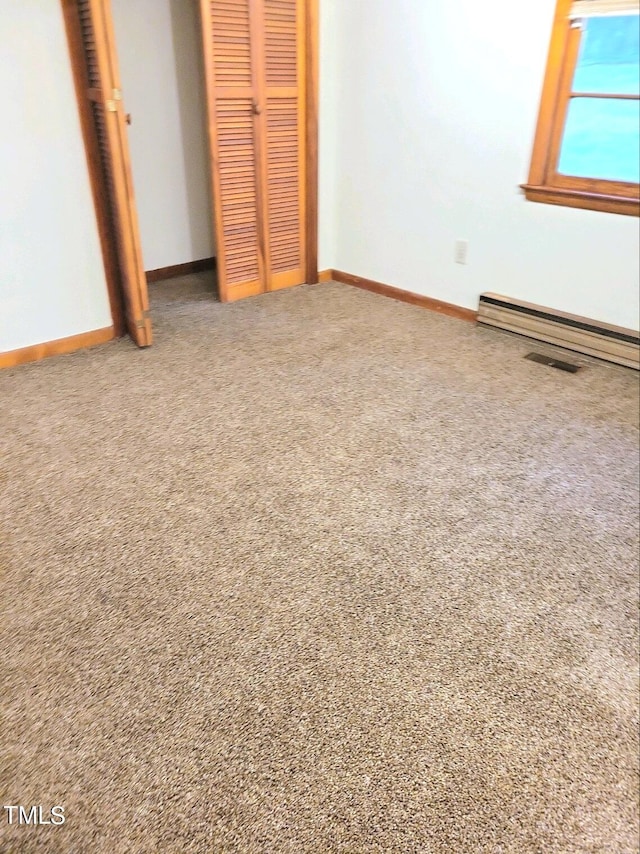 unfurnished bedroom featuring carpet floors, baseboard heating, a closet, and baseboards