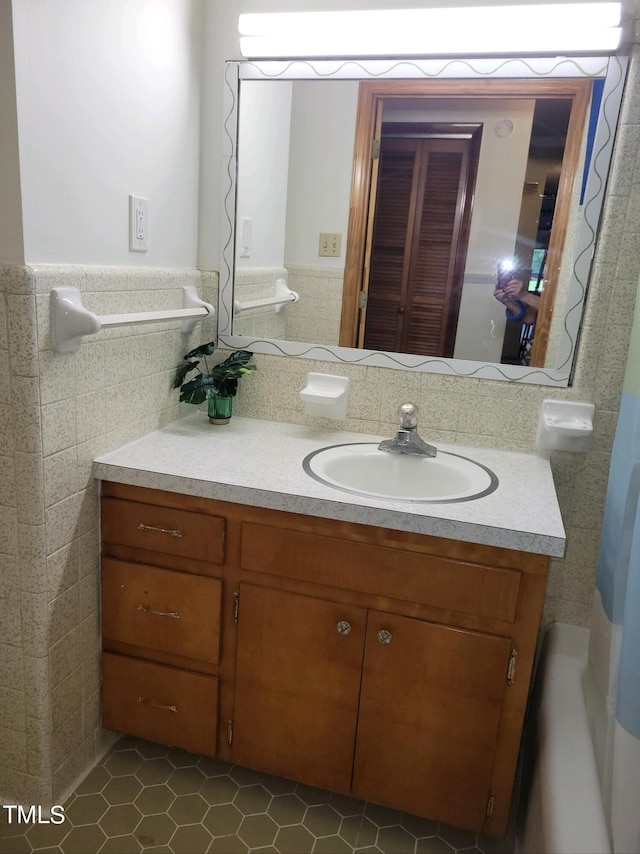 bathroom featuring tile walls, a wainscoted wall, and vanity