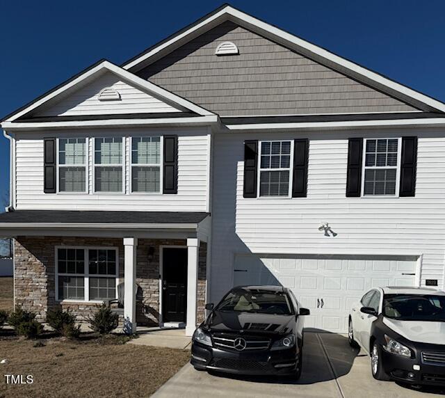 view of front facade featuring a garage, concrete driveway, and stone siding