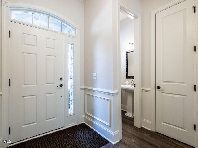 foyer entrance with a wainscoted wall, dark wood finished floors, and a decorative wall