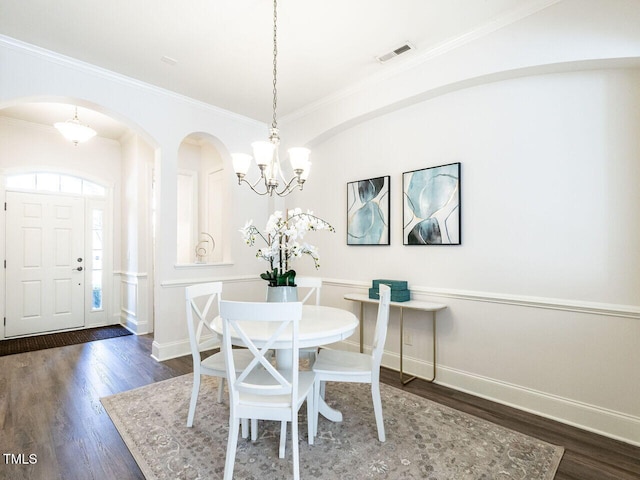 dining room with baseboards, visible vents, wood finished floors, and ornamental molding